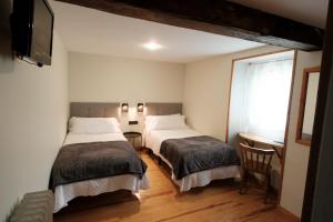 a bedroom with two beds and a tv and a window at Hosteria de Zubiri in Zubiri