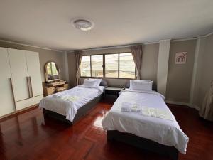 a bedroom with two beds and a window at Urban Grace in Bangkok