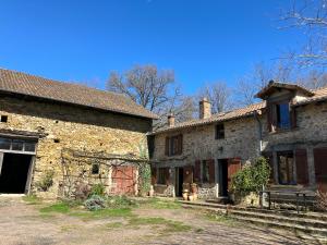 an old stone house with a gate in a yard at La Maison de la Treille in La Chapelle-Montbrandeix