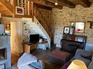 a living room with a staircase and a desk with a television at La Maison de la Treille in La Chapelle-Montbrandeix