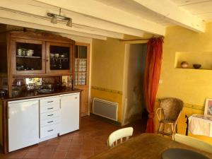 a kitchen with white cabinets and a table in a room at La Maison de la Treille in La Chapelle-Montbrandeix