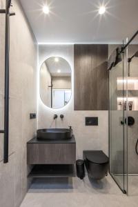 a bathroom with a sink and a toilet and a mirror at Sea Whisper apartamentai Daukanto g Palanga in Palanga