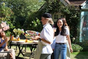 una donna in piedi accanto a una donna che tiene in mano un piatto di cibo di Coastguard Cottage a Ventnor