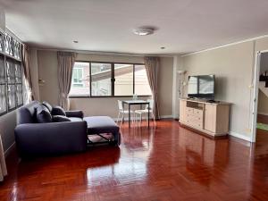 a living room with a couch and a tv at Urban Grace in Bangkok