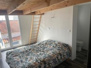 a bedroom with a bed and a ladder and windows at Sion sur locean - trois chambres in Saint-Hilaire-de-Riez