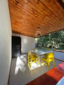 a dining room with a table and two yellow chairs at Casa da Dorinha in Teresópolis
