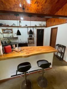 a kitchen with a wooden counter and two bar stools at Casa da Dorinha in Teresópolis