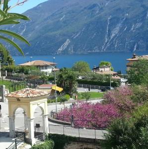 Blick auf einen See und ein Gebäude mit lila Blumen in der Unterkunft Hotel Villa Grazia in Limone sul Garda