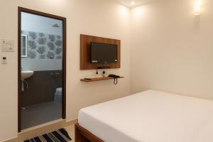 a bedroom with a bed and a tv and a bathroom at PY OLLIV Chennai THIRUVALLUR in Kaklūr