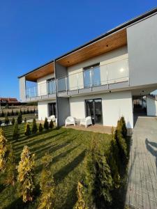 a large white house with two white chairs in the yard at Apartamenty Łuska w Dębinie in Debina