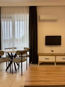 a living room with a television and a table and chairs at Ayshira Aparts in Kemer