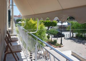 a balcony with chairs and an umbrella on a street at Ann's apartment II in Lixouri