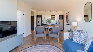 a living room with a blue couch and chairs and a table at Table Mountain View Apartment in Cape Town