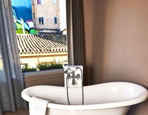 a bathroom with a bath tub and a window at iFeel Athens Suites in Athens