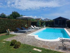 a swimming pool with chairs and an umbrella at Rossodisera in Sarzana