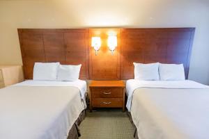 ein Hotelzimmer mit zwei Betten und einer Holzwand in der Unterkunft Gordon Hall Residence in Guelph