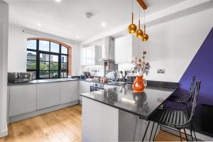 a kitchen with white cabinets and an orange vase on a counter at Dusk House in Birmingham