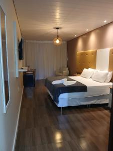 a hotel room with a large bed and a chair at Hotel Summer Beach Paripueira in Paripueira