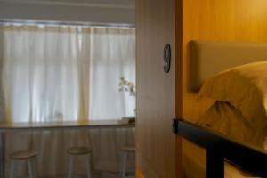a bedroom with a bed and a window with stools at Waveflo Hostel 浪花青旅 in Hong Kong