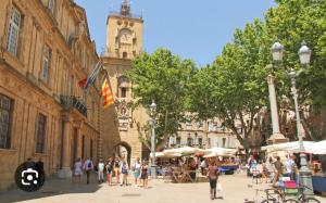 un groupe de personnes marchant dans une rue de la ville avec une tour d'horloge dans l'établissement Jolie maison indépendante avec jardin et piscine, à Aix-en-Provence
