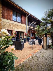 a patio of a building with chairs and flowers at Le Clos des Roses in Pérouges