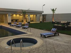 a patio with a pool and lounge chairs next to a building at Le Park Shaqra in Shaqra