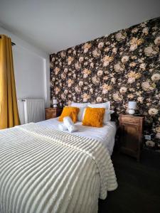 a bedroom with a bed with a floral wall at Le Clos des Roses in Pérouges