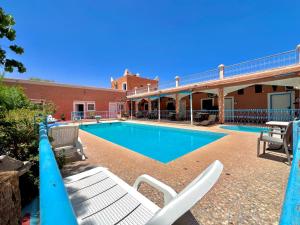 a swimming pool with lounge chairs next to a building at Hotel L'Arganier d'Ammelne-Tafraout in Tafraout