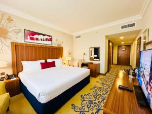 a hotel room with a bed and a flat screen tv at City Seasons Al Hamra Hotel in Abu Dhabi
