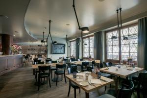 a restaurant with wooden tables and chairs and windows at Ochsen Lenzburg in Lenzburg