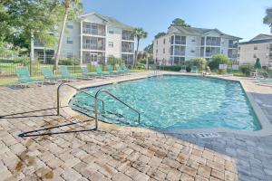 a large swimming pool with chairs in a apartment complex at 2 Bedroom Golf Course Oasis At River Oaks in Myrtle Beach