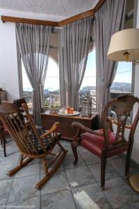 una stanza con sedie a dondolo, un tavolo e finestre di Villa Anna with Panoramic sea views a Pyrgos