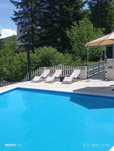 a blue swimming pool with lounge chairs and an umbrella at Vila Dolina Izvora in Sarajevo