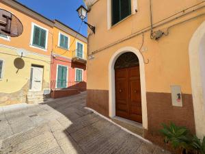 a building with a wooden door on a street at La Maddalena Tour Holiday Home - Residenza Alibertini in La Maddalena
