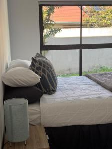 Un dormitorio con una cama con almohadas y una ventana. en Solar - powered Bryanston Home, en Johannesburgo