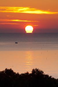 una puesta de sol sobre el océano con un barco en el agua en Hotel Belvedere, en Porto SantʼElpidio