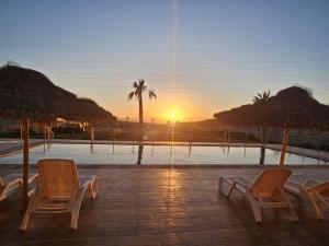 two chairs sitting in front of a pool at sunset at Villa Kazim in Berkane