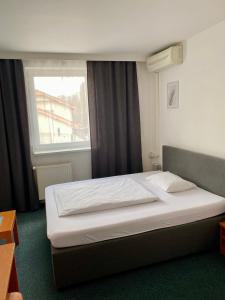 a bed in a hotel room with a window at Penzión Helios in Bratislava