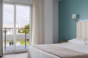 Un dormitorio con una cama y una ventana grande. en Hotel Azinheira by RIDAN Hotels, en Fátima