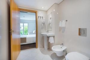 Un baño con inodoro, lavabo y cama. en Hotel Azinheira by RIDAN Hotels, en Fátima