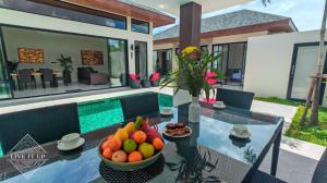 a table with a bowl of fruit on it in front of a house at Santi Tara Villas in Amphoe Koh Samui +274 photos