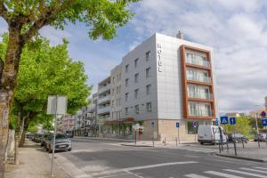 un edificio blanco en una calle de la ciudad con coches aparcados en Hotel Azinheira by RIDAN Hotels, en Fátima