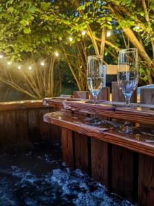 トンブリッジにあるBell Nook- Shepherd's hut with a spacious wood-fired hot tubの小川の横にある木製のテーブルの上に置かれた3つのワイングラス
