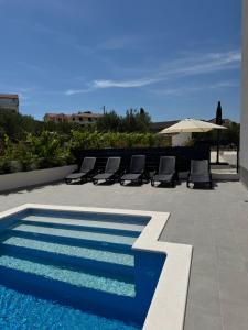 a pool with chairs and an umbrella on a patio at Čiovo Bay Apartment in Slatine