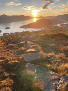 a sunset on a hill with rocks and a body of water at Petersstova in Ålesund