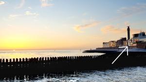 a pier with a lighthouse and the ocean at sunset at Zeezicht in Vlissingen