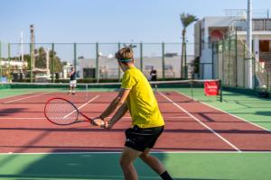 a man holding a tennis racket on a tennis court at Royal Savoy Sharm El Sheikh in Sharm El Sheikh