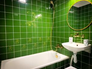 a green tiled bathroom with a sink and a bath tub at Sen nad Bałtykiem - Apartament z balkonem, Ustka in Ustka