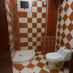 a bathroom with a toilet and a tiled wall at شاطئ البندقية للشقق المخدومة in Hafr Al Baten