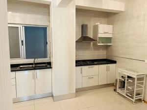 a kitchen with white cabinets and a sink and a window at Douceur de Vie in Praia